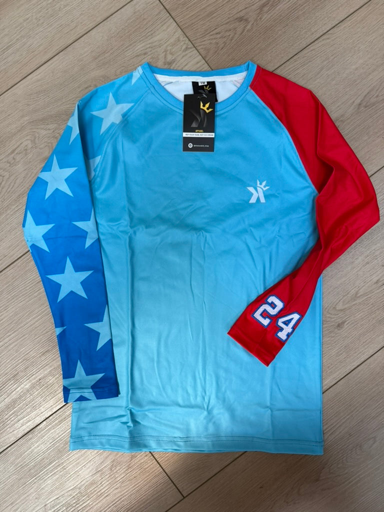 Light blue long sleeve shirt with a blue star print sleeve and a red sleeve featuring the number 24, laid flat on a wood floor.