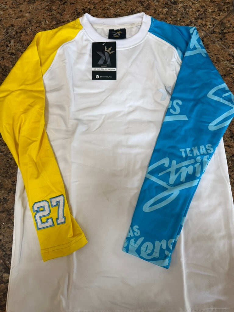 White long sleeve shirt with a yellow sleeve featuring the number 27 and a blue sleeve with printed team text, laid flat on a countertop.