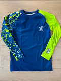 Navy blue long sleeve shirt with a neon green sleeve and a blue-and-white paint splatter print sleeve featuring the number 5, laid flat on a wood floor.