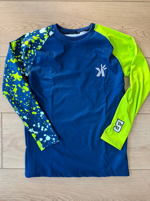 Navy blue long sleeve shirt with a neon green sleeve and a blue-and-white paint splatter print sleeve featuring the number 5, laid flat on a wood floor.